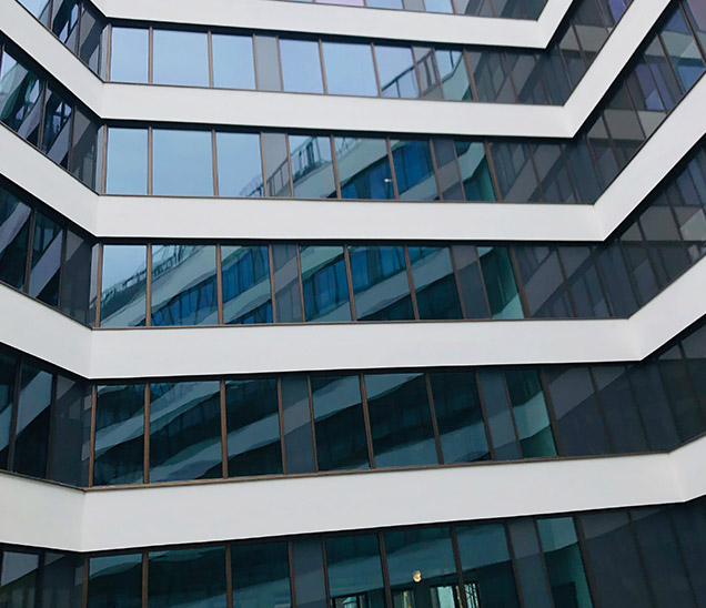 Gestufte Fassade mit weißen Putzbändern und Glas